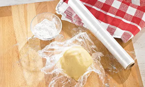 Teig ist zu einer Kugel zusammengeformt in Frischhaltefolie gewickelt