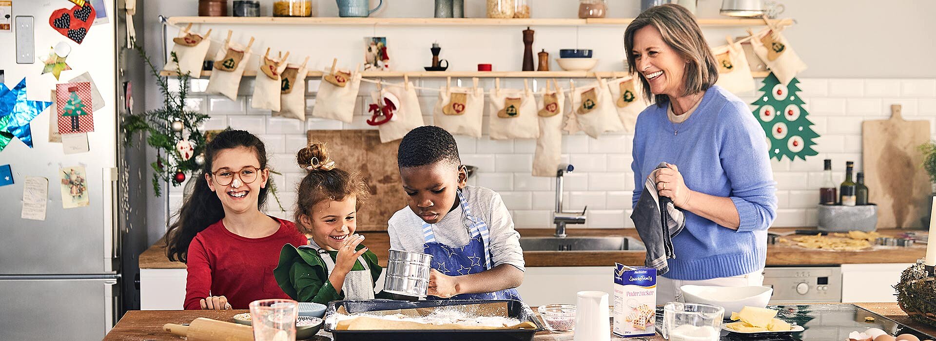 Frau backt mit Kindern Kekse nach dem Rezept und mit Produkten von SweetFamily