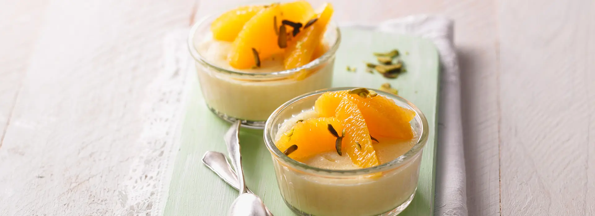 In zwei Schalen ist ein heller Pudding mit Orangensteifen verziert. 