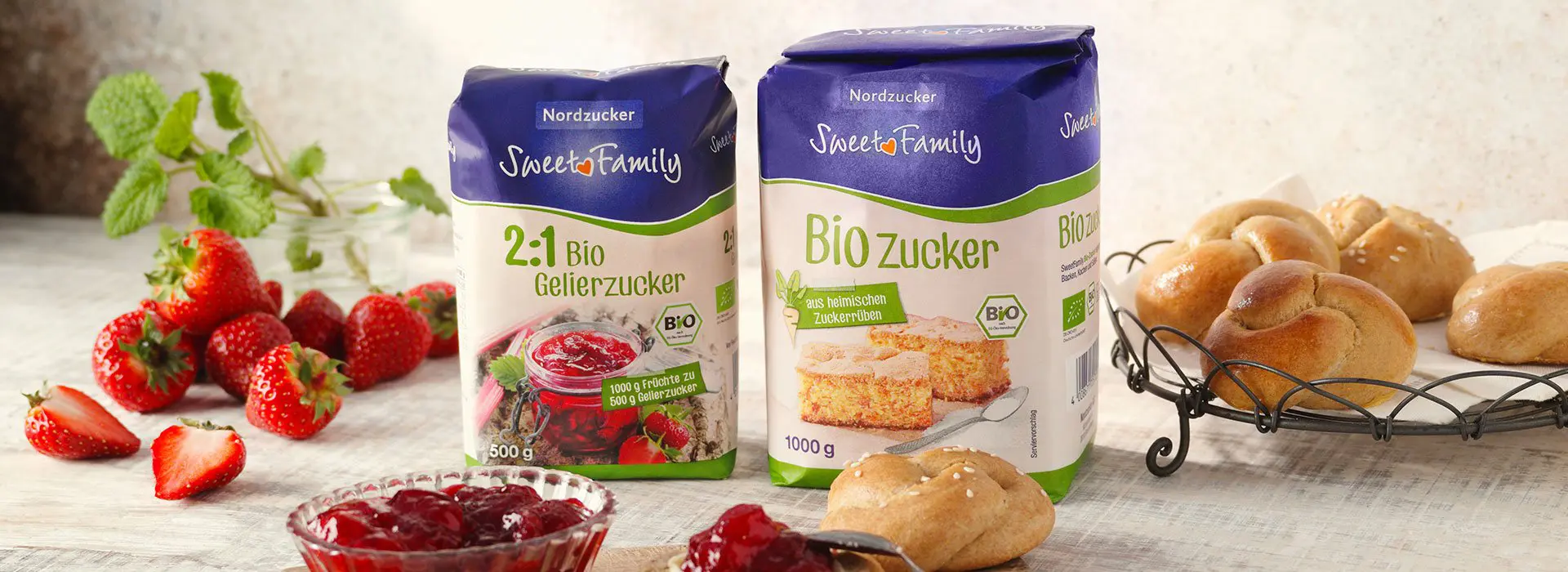 Zucker Produkte von SweetFamily aufgestellt. Umringt von Brötchen, Marmeladengläsern und frischen Erdbeeren