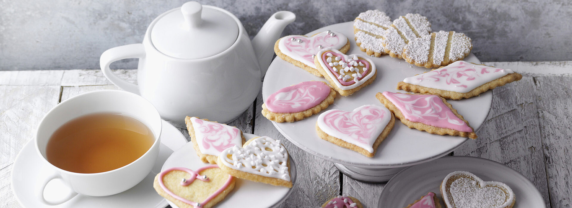 Butterplätzchen nach dem Rezept von SweetFamily schön präsentiert neben einer Tasse Tee und einer Teekanne