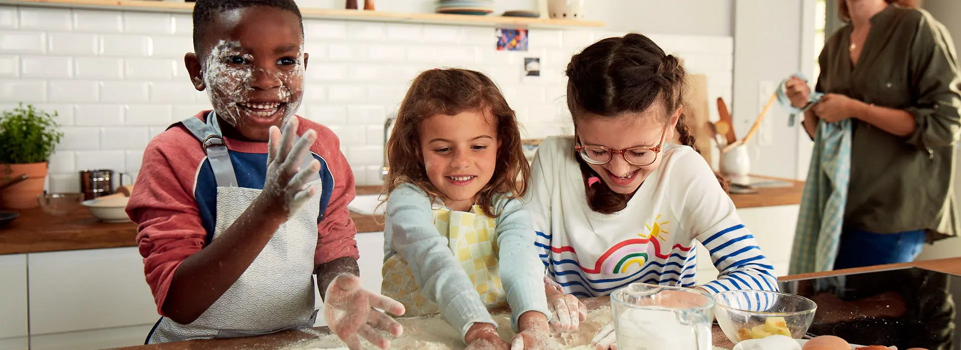 Zwei Kinder haben Spaß beim Backen, ihre Hände sind voller Mehl, während sie Teig kneten.