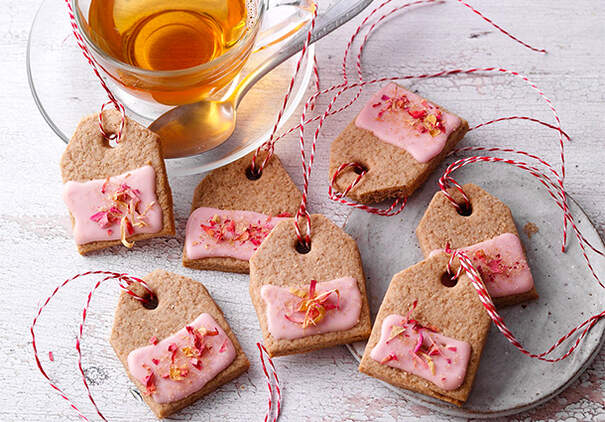 Chai-Teebeutel-Kekse mit rosa Zuckerguss und Rosenblüten