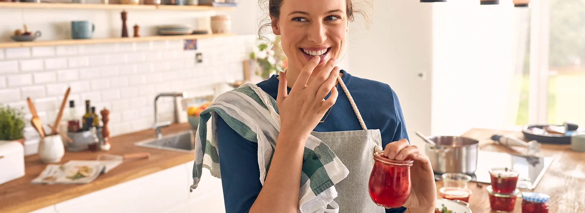 Eine Frau hält glücklich ihre frisch eingetopfte Marmelade in der Hand.