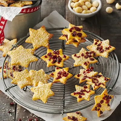 Macadamia-Nuss-Cookies liegen auf einem Kuchenrost. Teilweise sind sie bereits verziert