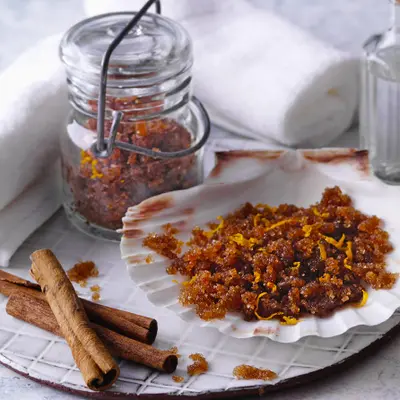 Teller und Einmachglas mit einem Peeling aus Blutorange und Zimtstangen