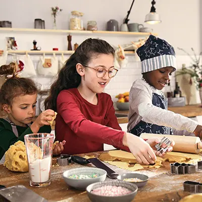 Drei Kinder backen fröhlich Weihnachtsplätzchen