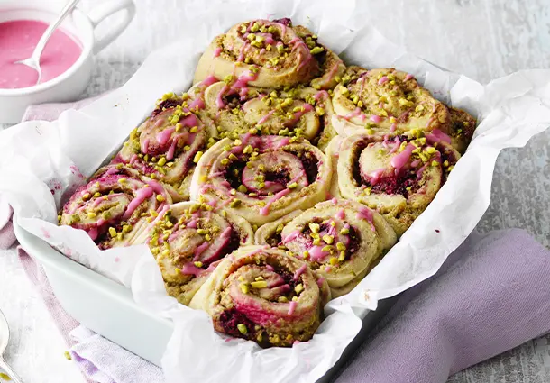 Vegane Hefeschnecken mit Pistaziencreme und Himbeeren, rosa Himbeer-Puderzuckerglasur und gehackten Pistazien