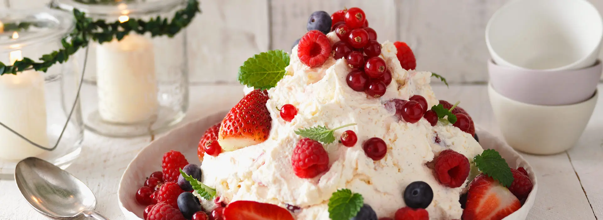 Ein großer Berg weißer Creme auf einem Teller und verschiedenen Beeren als Topping.