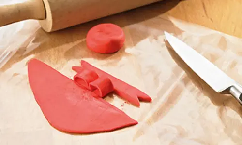 Fondant liegt auf Backpapier in Streifen geschnitten und in Bällchen geformt.  
