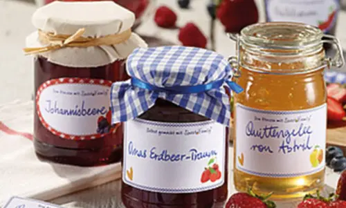 9. Beschrifte … drei befüllte Gläser mit verschiedenen Marmeladen stehen voreinander aufgereiht. Die Gläser sind alle mit süßen Ettiketten verziert und beschriftet.