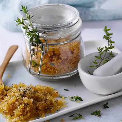 Weißer Teller mit einem Einmachglas und einem Peeling aus Lemongras und Thymian