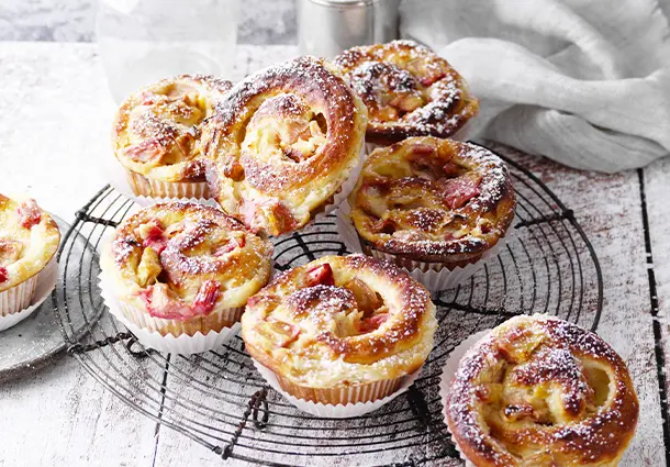 Hefeschnecken mit Rhabarberstückchen und cremiger Schmandfüllung, in Muffinformen goldbraun gebacken und mit Puderzucker bestäubt