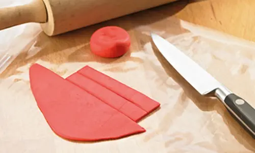 Fondant liegt auf Backpapier in Streifen geschnitten.