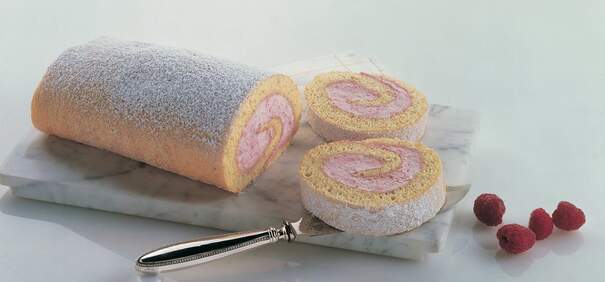 Eine Biskuitrolle mit hellen und rosafarbenen Schichten ist mit Puderzucker bestäubt und wird von Himbeeren begleitet.