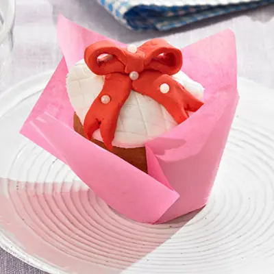 Cupcake mit einer roten Schleife aus Fondant mit essbaren Perlen.