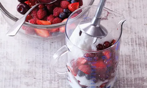 In einem hohen Gefäß sind verschiedene Beeren mit  Einmachzucker enthalten.