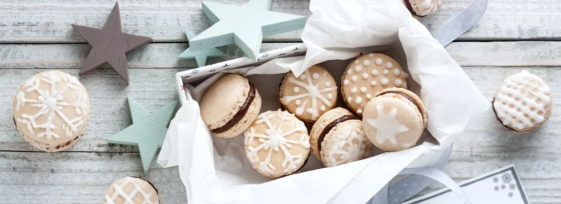 Schneeflockenförmige Zuckergussverzierung auf Macaronförmigen Plätzchen mit Schokoladenfüllung