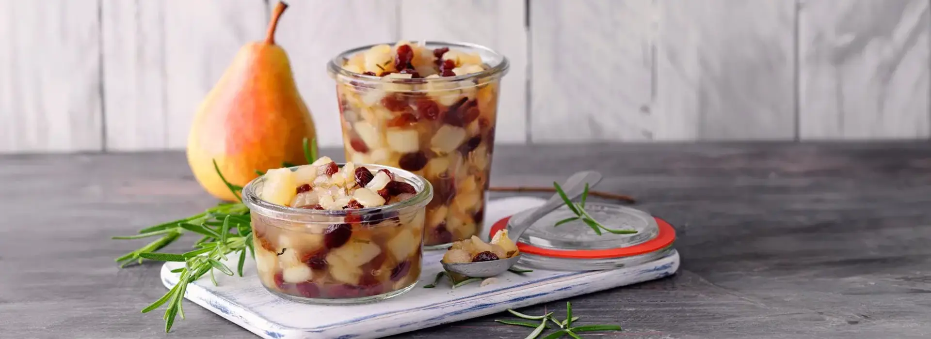 Auf einem Brett stehen zwei Schalen mit eingemachtem Obst in kleine Würfel geschnitten.