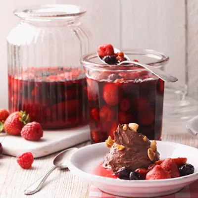 Zwei große Glasgefäße enthalten eingelegte früchte. Davor steht ein kleiner Dessertteller mit einer Schokoeis.