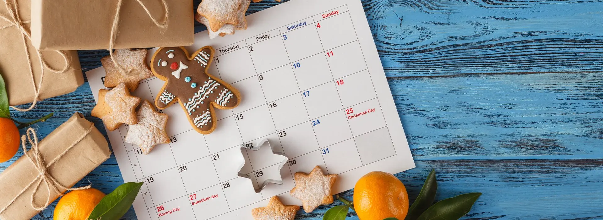Tisch auf dem ein Kalender liegt. Darum sind Kekse und kleine Geschenke verstreut.