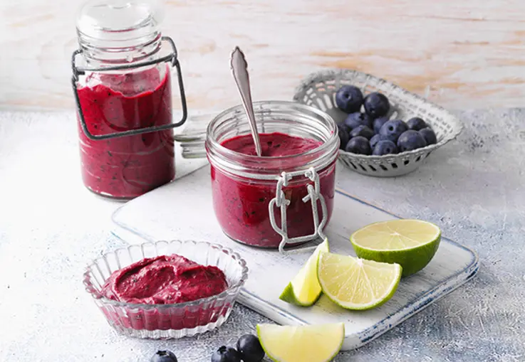 Gläser mit cremigem, dunkelviolettem Blaubeer-Curd mit glatter, glänzender Oberfläche.