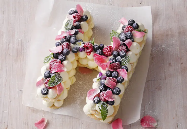 Kleine runde Torte mit heller Creme, bedeckt mit frischen Heidelbeeren und glänzendem Fruchtspiegel.