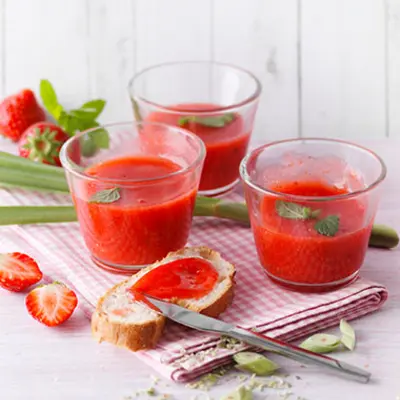 Gläser mit Erdbeeraufstrich und einem Butterbrot, das mit der Marmelade bestrichen ist