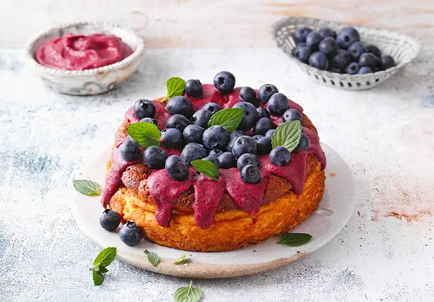 Kleiner Käsekuchen mit glänzendem Blaubeer-Topping und frischen Beeren sowie Minze.