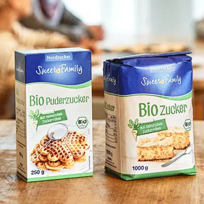 Zwei Packungen Sweet Family Biozucker stehen auf einem Holztisch