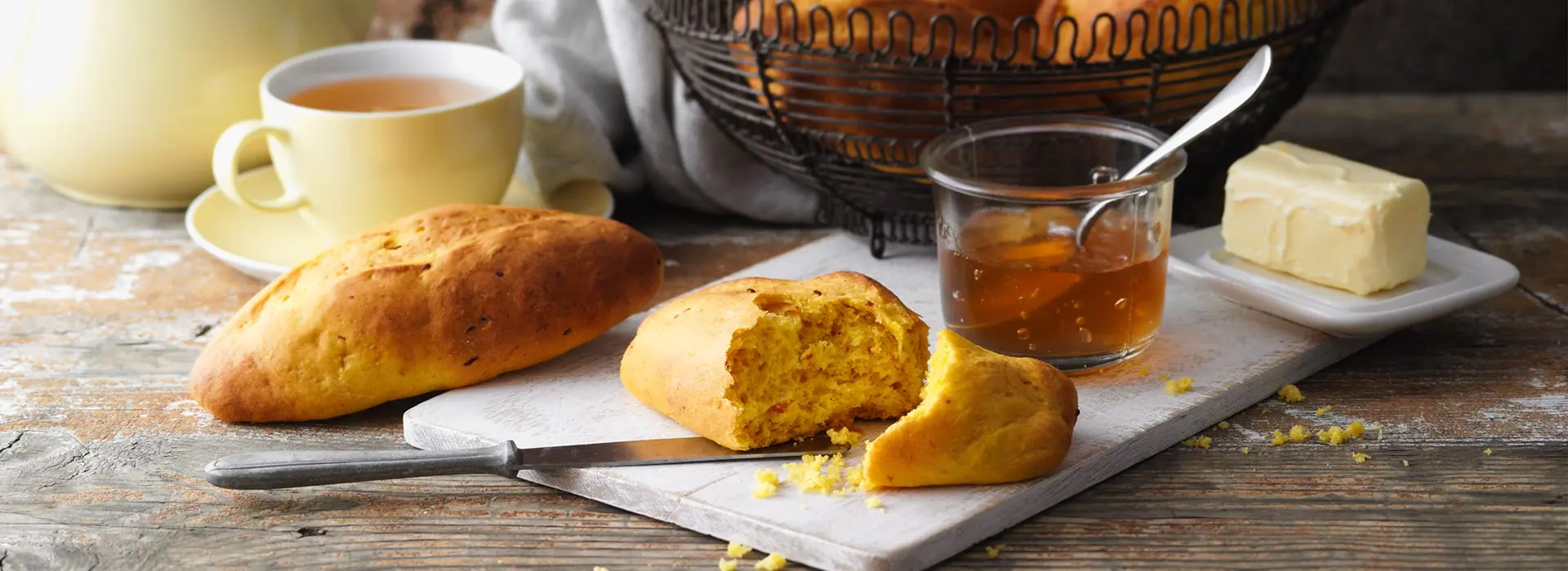 Selbstgebackene Brötchen liegen auf einem Brett serviert mit Butter und Honig