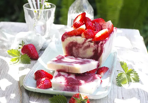 Gefrorene Scheiben von cremigem Joghurteis mit zarten Erdbeerwirbeln und frischen Beeren.