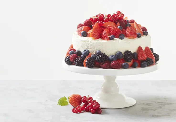 Mehrschichtige Torte mit heller Mascarponecreme, dekoriert mit frischen gemischten Beeren.