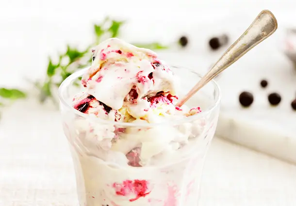Cremiges Cheesecake-Eis zeigt sahnig weiße Farbe mit dunkelvioletten Johannisbeer-Swirls, die sich marmoriert durchziehen