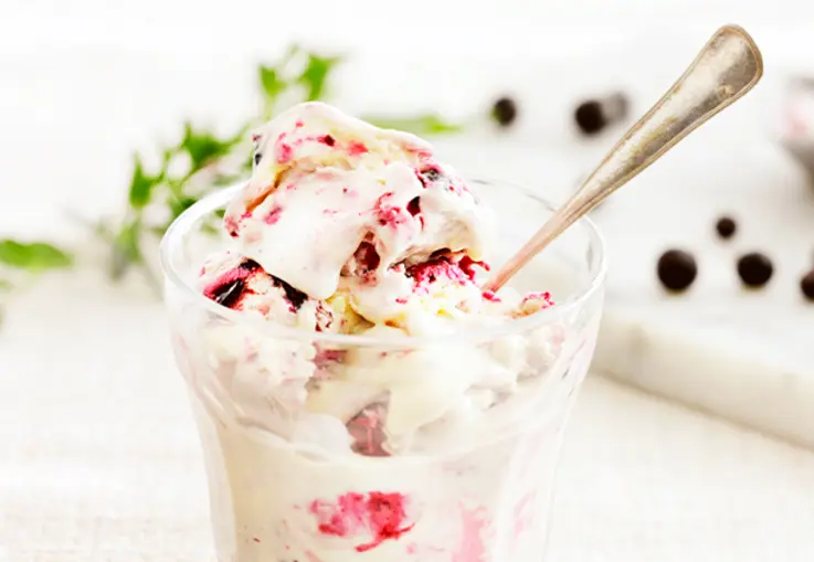 Cremiges Cheesecake-Eis zeigt sahnig weiße Farbe mit dunkelvioletten Johannisbeer-Swirls, die sich marmoriert durchziehen