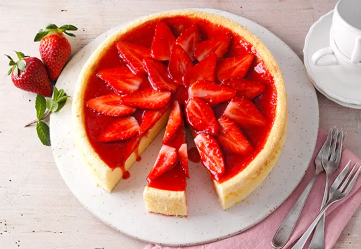 Luftiger Cheesecake mit glänzendem Erdbeerspiegel und frischen Erdbeerscheiben.
