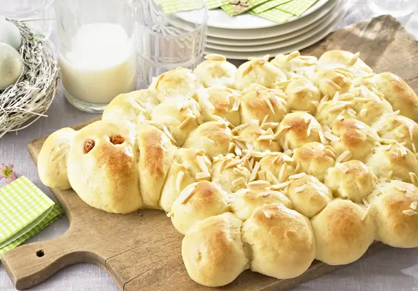 Ein aus Hefeteig geformtes Osterlamm aus vielen Teigbällchen, mit Rosinen als Augen und Mandelblättchen verziert, goldbraun gebacken