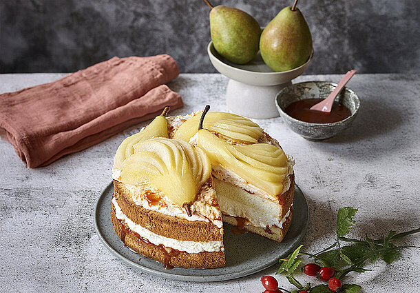 Buiskuittorte dekoriert mit halbierten und pochierten Birnen gebacken mit Hagebutten und schön angerichtet
