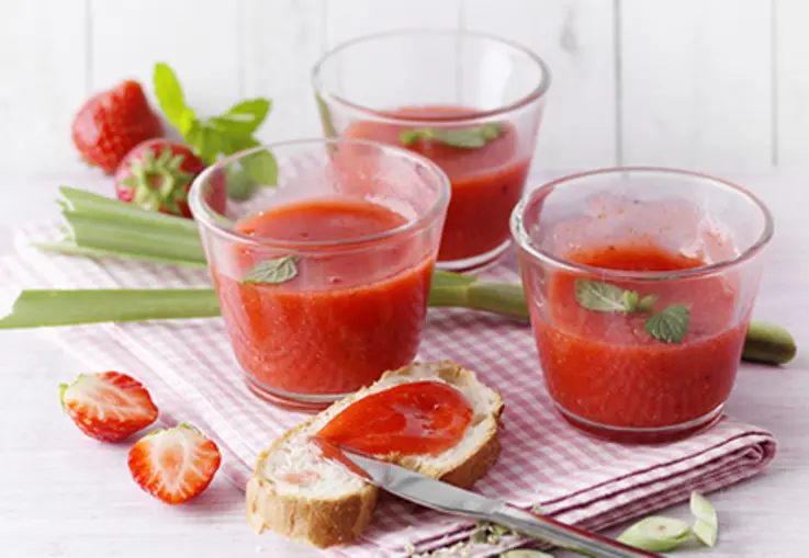 Drei kleine Gläser mit zartrosa Erdbeer‑Zitronengras‑Aufstrich, dazu frische Beeren, Brotstückchen und Zitronengrasstängel