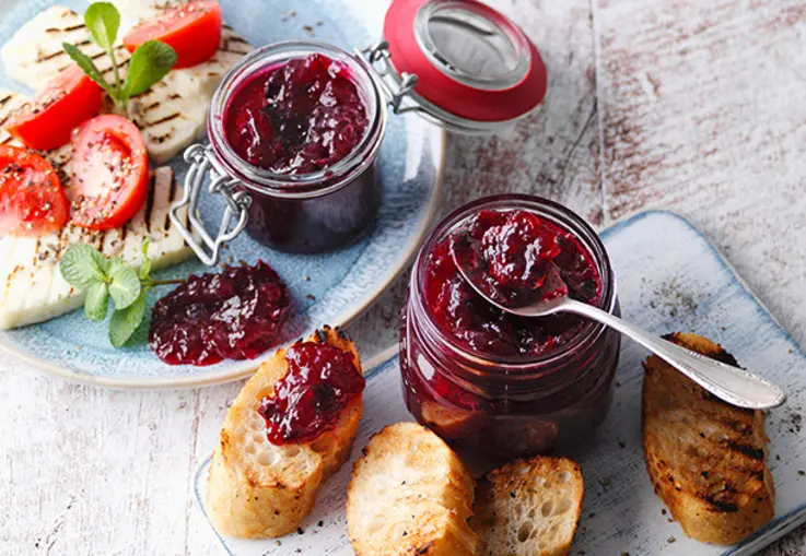 Dunkles Relish mit Stückchen von Johannisbeeren und Apfel, sichtbar gewürzt mit Kräutern und Gewürzen.